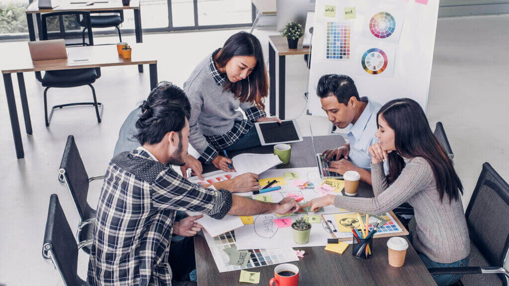 Female Creative director team leader brainstorm branding project with designer team at meeting table