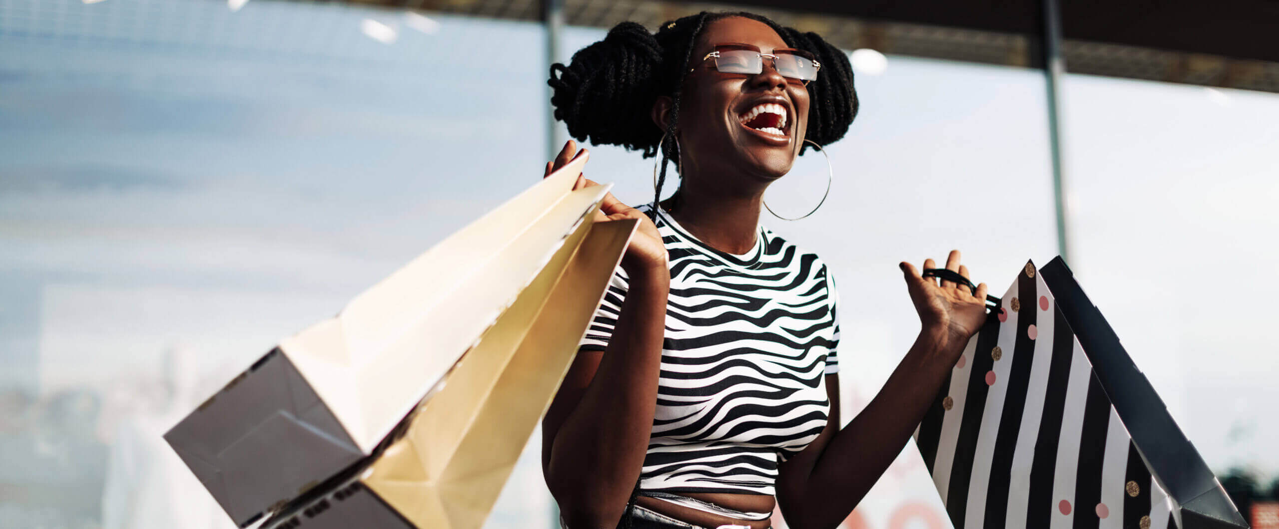 woman wearing classes smiling in the air while holding shopping bag 