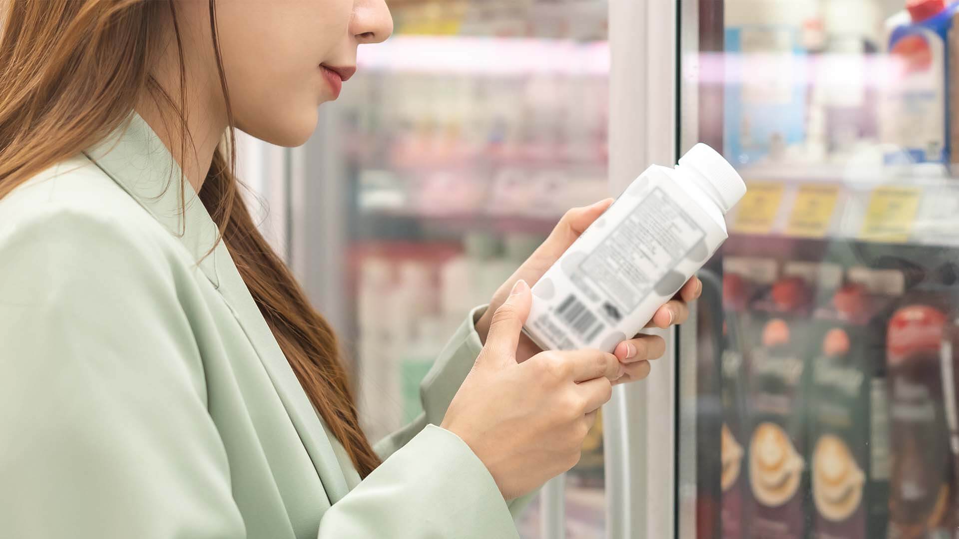 Asian woman looking at labelling on bottle 