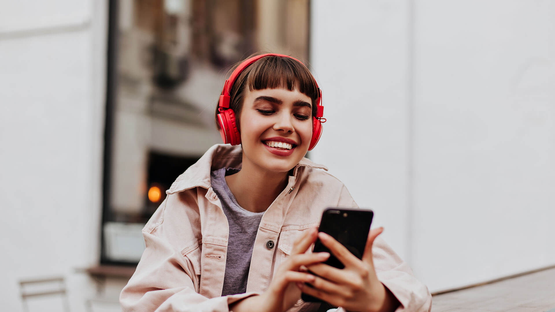 Woman smiling with red headphones smiling at her phone