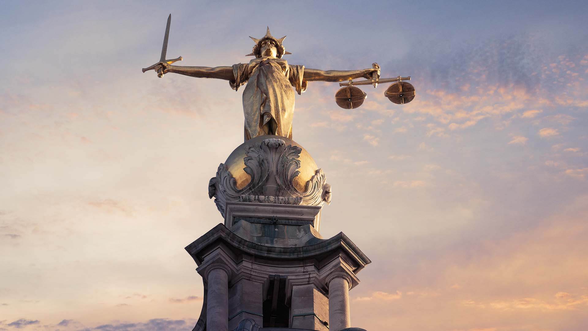 Lady justice on top of the crown court while sun is setting 